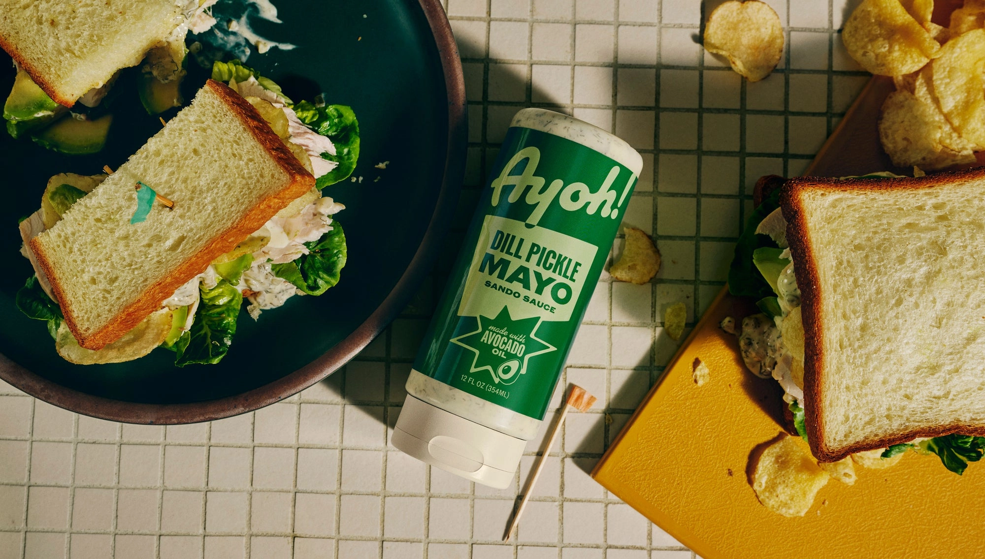 Ayoh Dill Pickle Mayo bottle resting on a sandwich with lettuce
